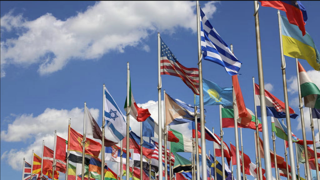 flags of many countries flying on flagpoles looking up to the sky.